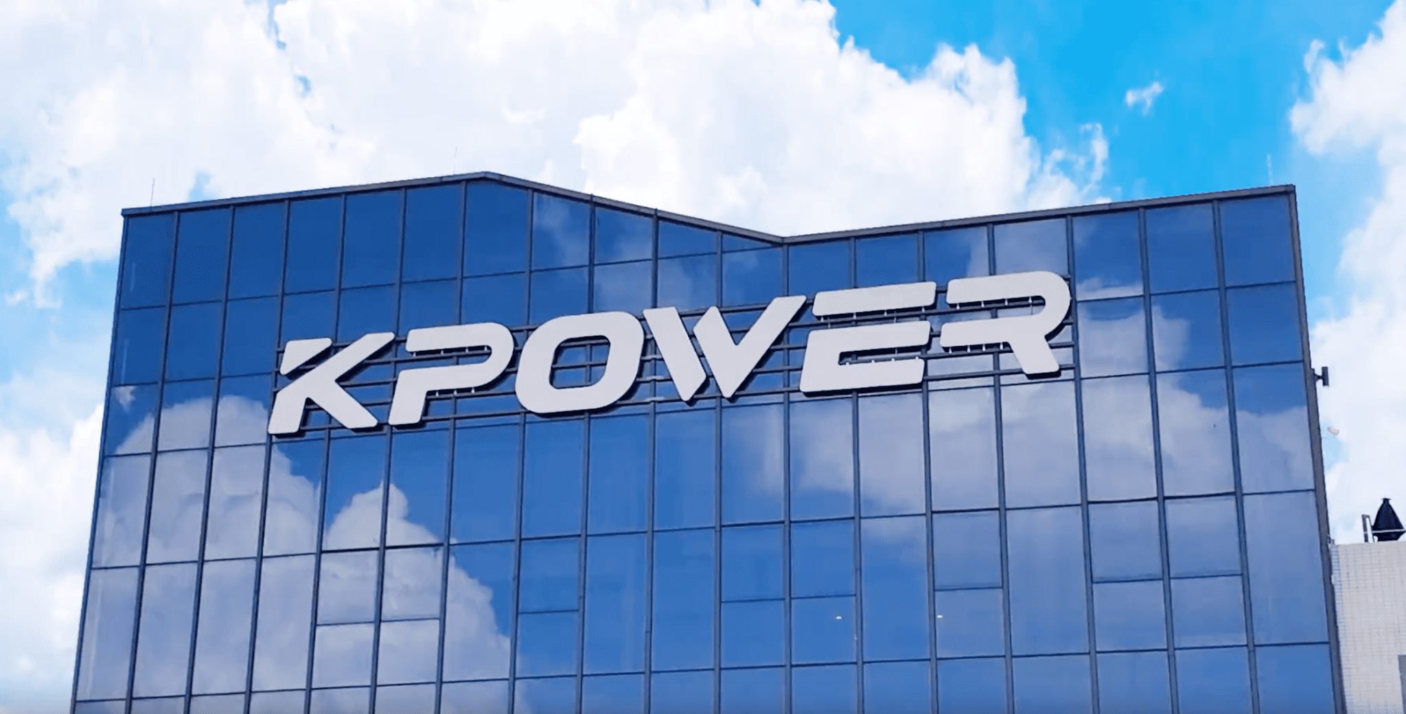 Modern corporate building with blue glass facade featuring the KPOWER logo in large white letters.